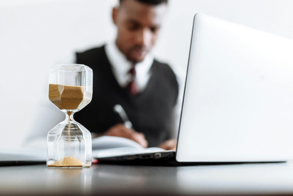 pexels photo 5060979 5060979 Businessman at desk with hourglass indicating time management and daily work routine.